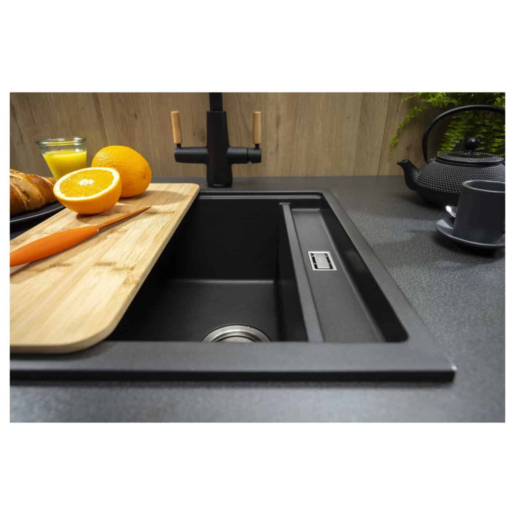 Sleek black composite kitchen sink with integrated drainage, modern black tap, and minimalist black countertop with a wooden chopping board and breakfast items, featuring stylish black kitchen accessories.