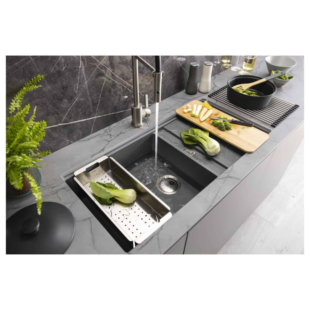 Sleek modern black kitchen sink with stainless steel accessories and a grey marble countertop, featuring fresh vegetables and a contemporary kitchen setup.