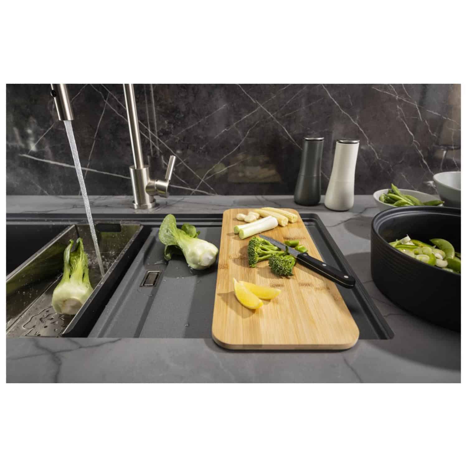 Fresh vegetables being washed in a modern kitchen sink with a sleek, stainless steel tap, wooden chopping board, and black countertop, demonstrating high-quality kitchen fixtures and fixtures.