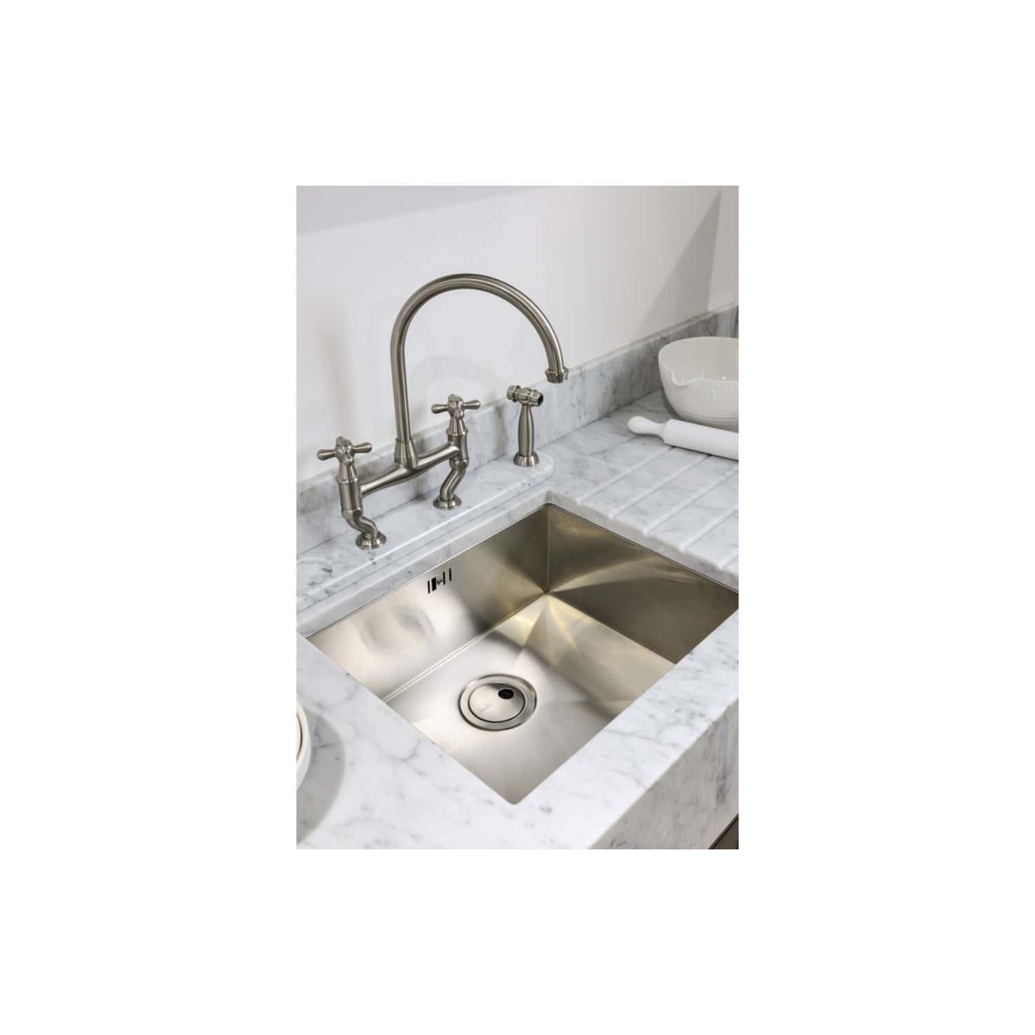 Polished stainless steel kitchen sink with traditional dual-handle faucet, installed in a modern marble countertop, perfect for premium bathroom or kitchen renovation.