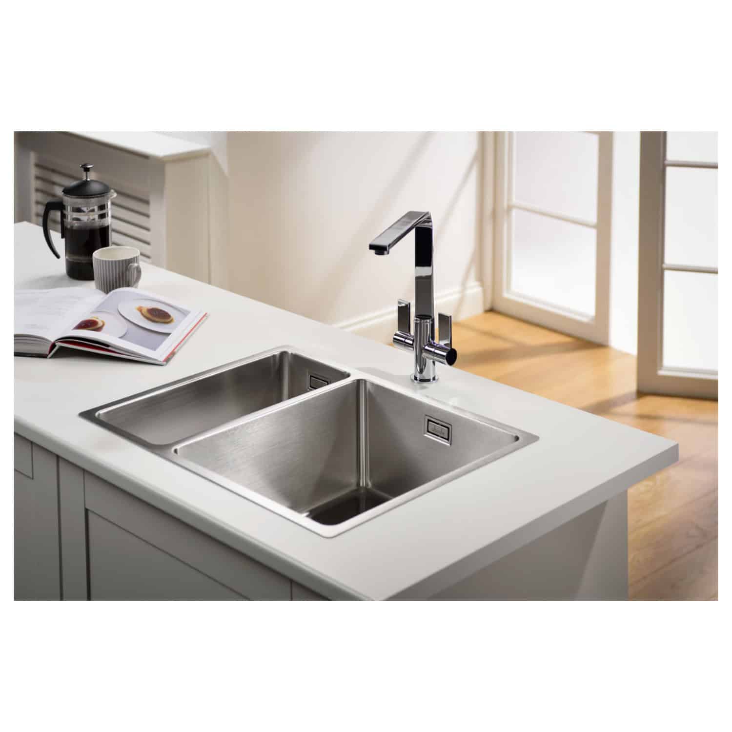 Stainless steel kitchen sink with modern chrome faucet on a white countertop in a bright, contemporary kitchen setting. Perfect for stylish and functional kitchen spaces.