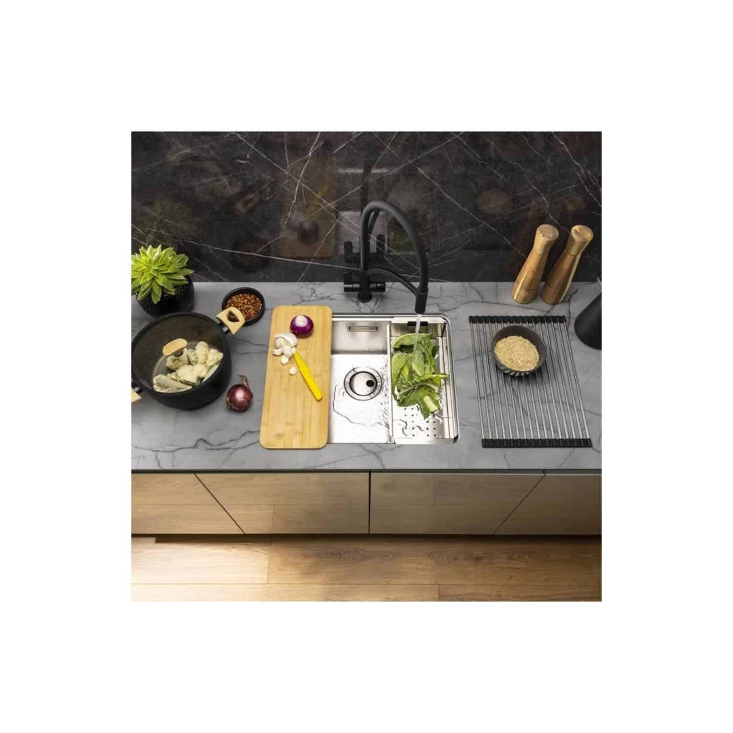 Modern kitchen sink with black faucet and grey marble countertop, surrounded by cooking utensils, fresh ingredients, and seasonal vegetables, highlighting stylish and functional kitchen design.