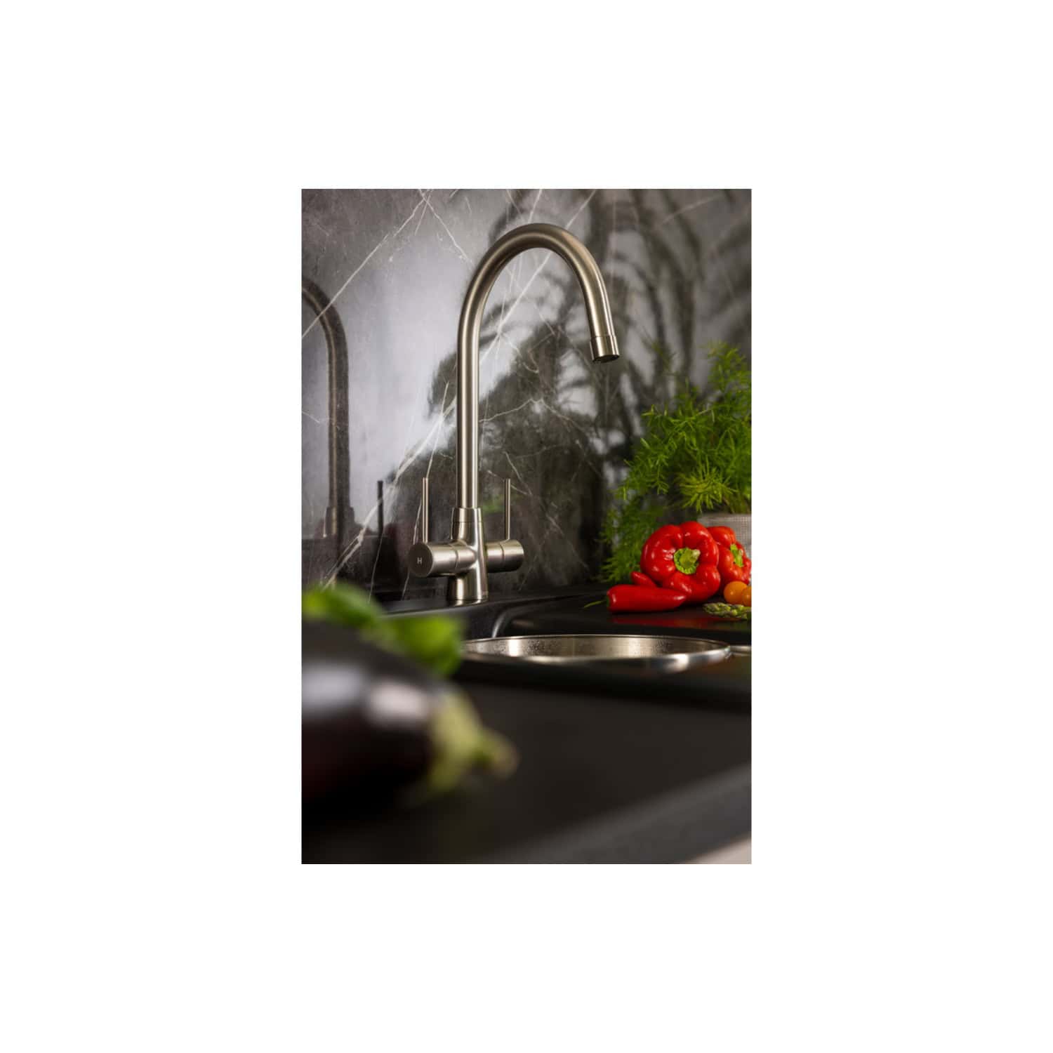 Sleek stainless steel kitchen tap with modern design in a contemporary kitchen setting, complemented by fresh vegetables and greenery, perfect for stylish and functional kitchen spaces.