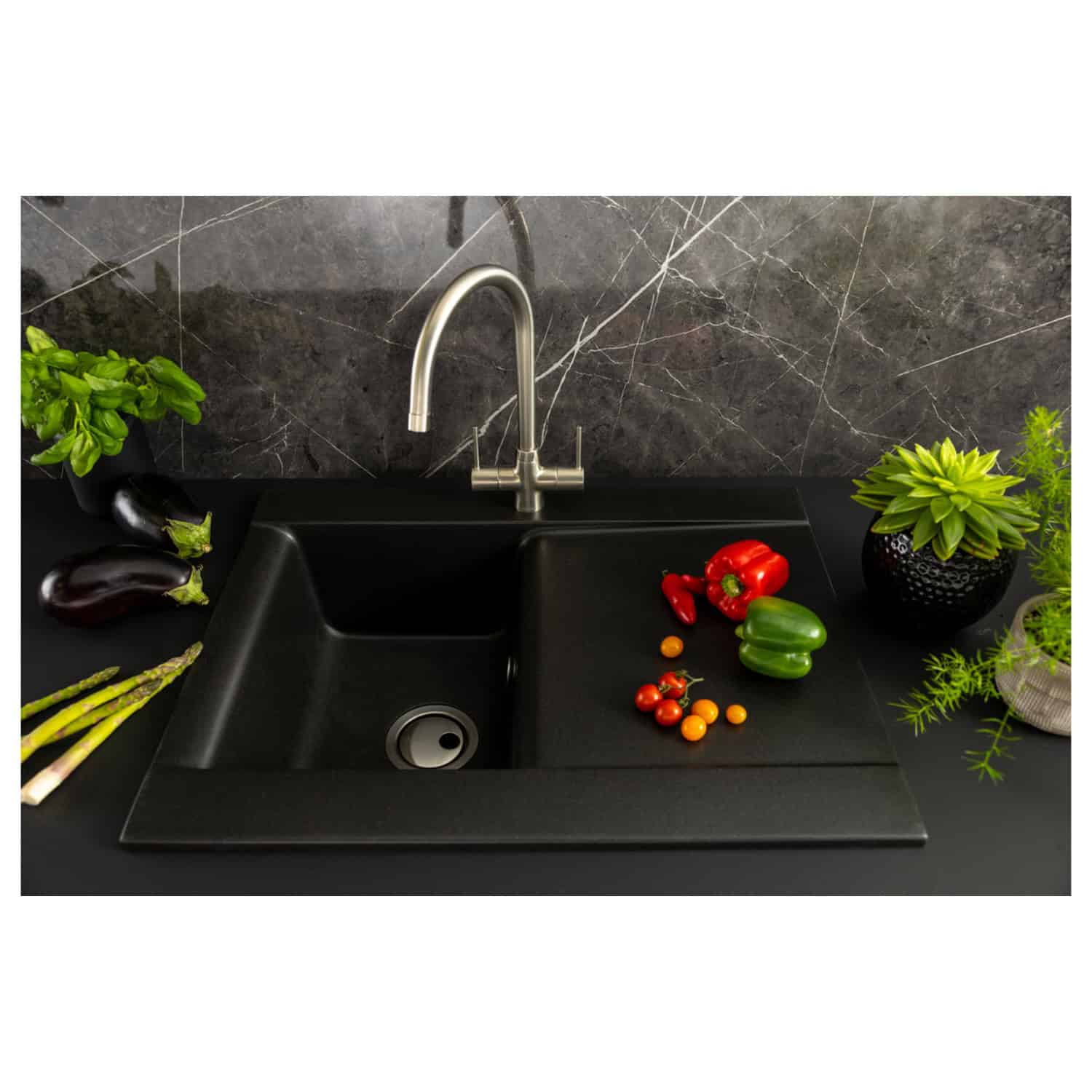 Black kitchen sink with modern stainless steel faucet and fresh vegetables on black countertop with marble backsplash, showcasing stylish and functional Bubly Bathrooms design.
