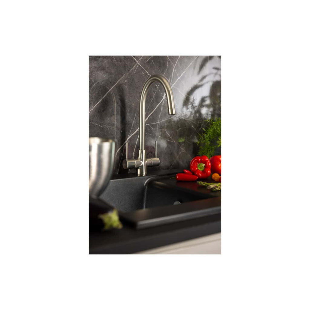 Sleek stainless steel kitchen tap with modern design, installed over a dark marble backsplash, surrounded by fresh red peppers, tomatoes, asparagus, and herbs, combining functionality and style.