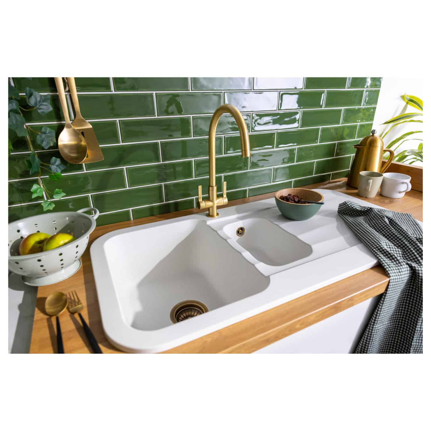 Shiny white double kitchen sink with brass faucet and green tiled backsplash; stylish, functional kitchen design featuring modern appliances and decor from Bubly Bathrooms.