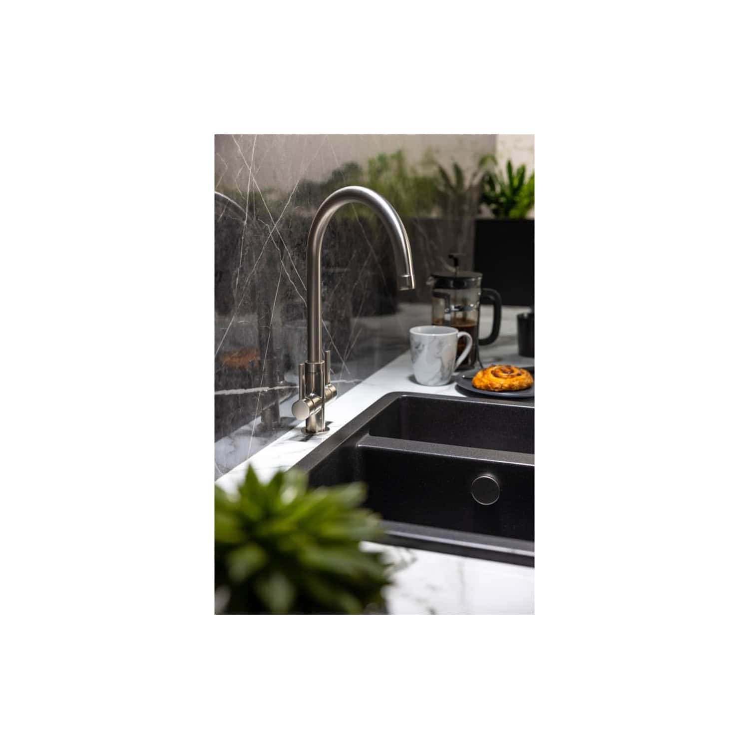 Shiny stainless steel kitchen sink faucet with a modern curved design in a contemporary kitchen setting.
