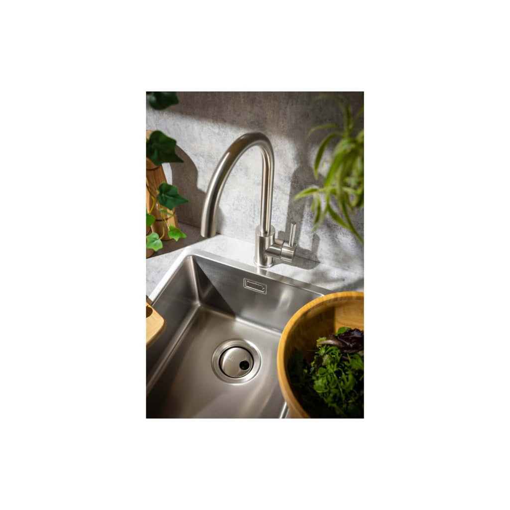 Sleek stainless steel kitchen sink with modern chrome faucet, surrounded by fresh herbs and greenery, creating a stylish and functional space for food prep and cleaning.