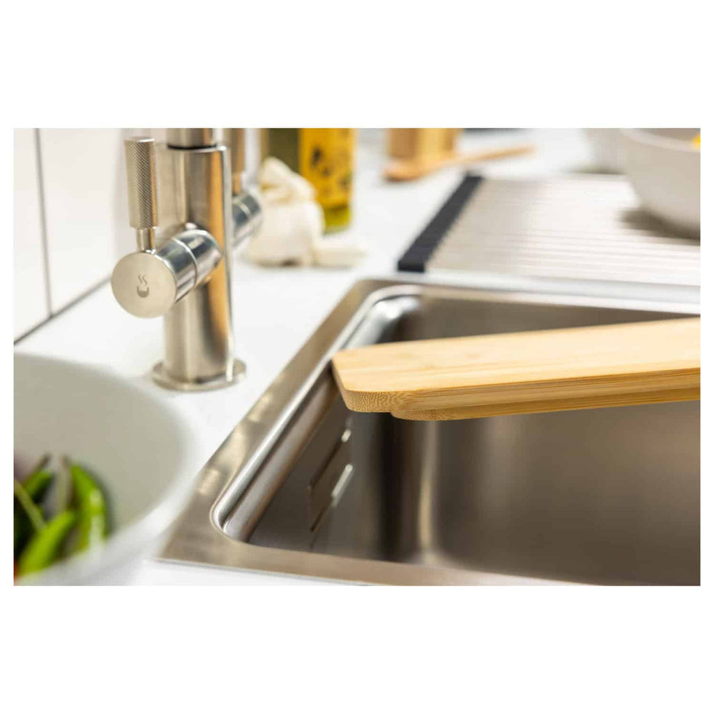 Shiny stainless steel kitchen sink with a modern chrome faucet and a wooden cutting board, part of Bubly Bathrooms' contemporary bathroom and kitchen design solutions.