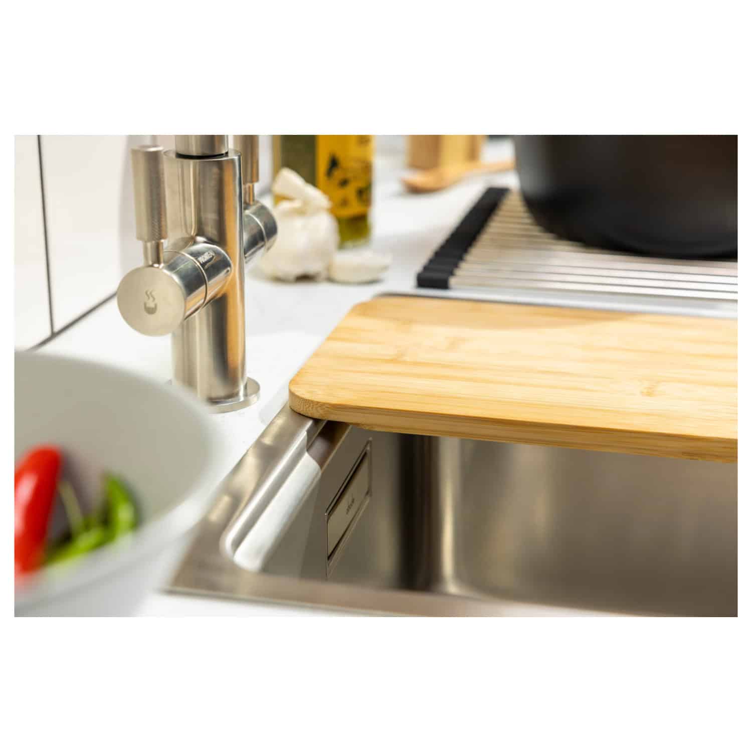 Shiny stainless steel kitchen sink with modern chrome tap, wooden chopping board, and various kitchen essentials in the background, highlighting stylish and functional bathroom and kitchen design.