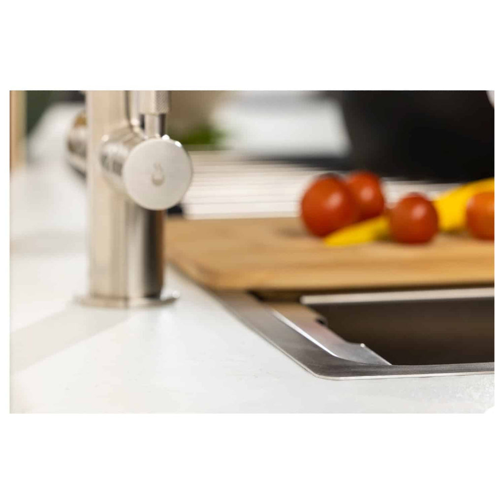 Shiny kitchen sink and modern chrome faucet with fresh tomatoes and a banana on a wooden cutting board, showcasing stylish and functional kitchen bathroom fixtures.