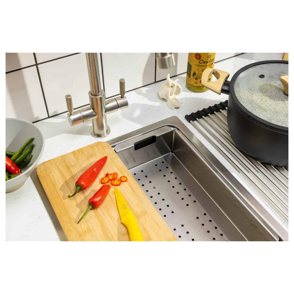 Red and green chilli peppers chopping on wooden cutting board in modern kitchen with stainless steel sink and cooking pot.