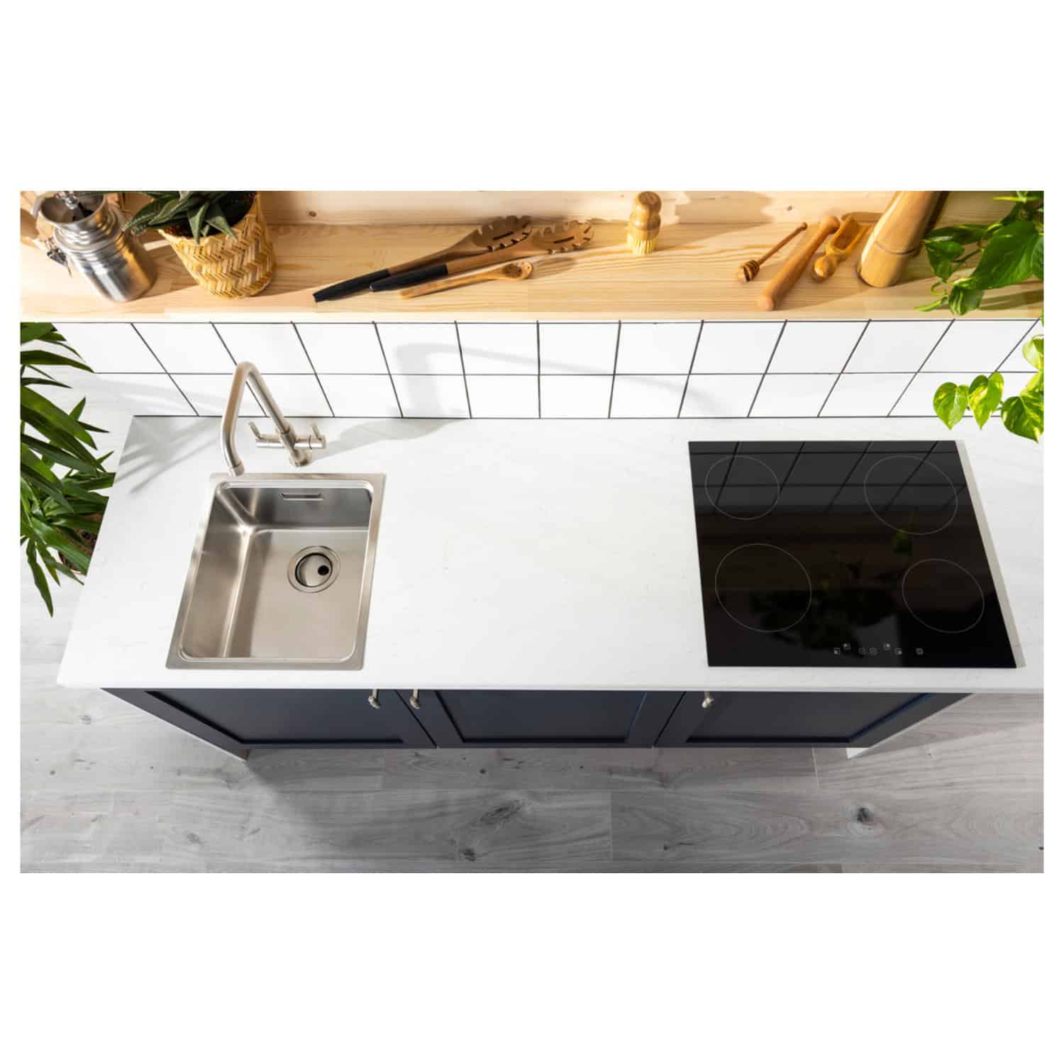 Sleek kitchen countertop with stainless steel sink and modern electric induction cooktop, black cabinetry, and a wooden shelf with kitchen tools and plants for stylish and functional kitchen design.