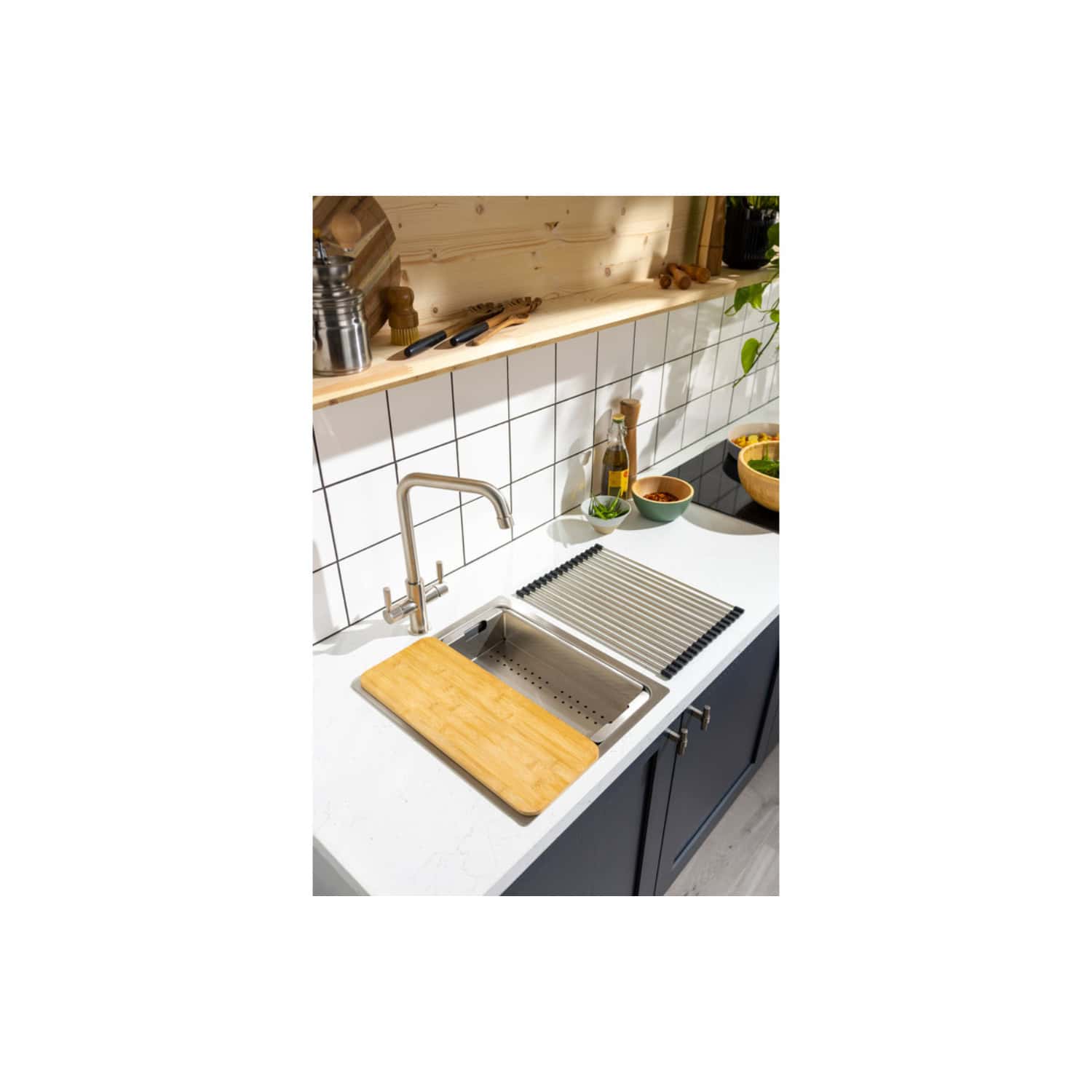Sleek modern kitchen sink with stainless steel basin, wooden chopping board, and drying rack, featuring a contemporary design with white countertops, tiled backsplash, and stylish organisation.