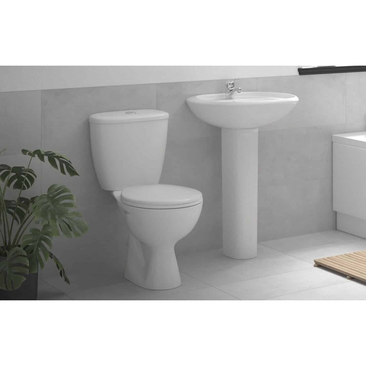White modern toilet and pedestal sink in minimalist style bathroom, with grey wall tiles and a potted plant, showcasing elegant bathroom fixtures and contemporary design.