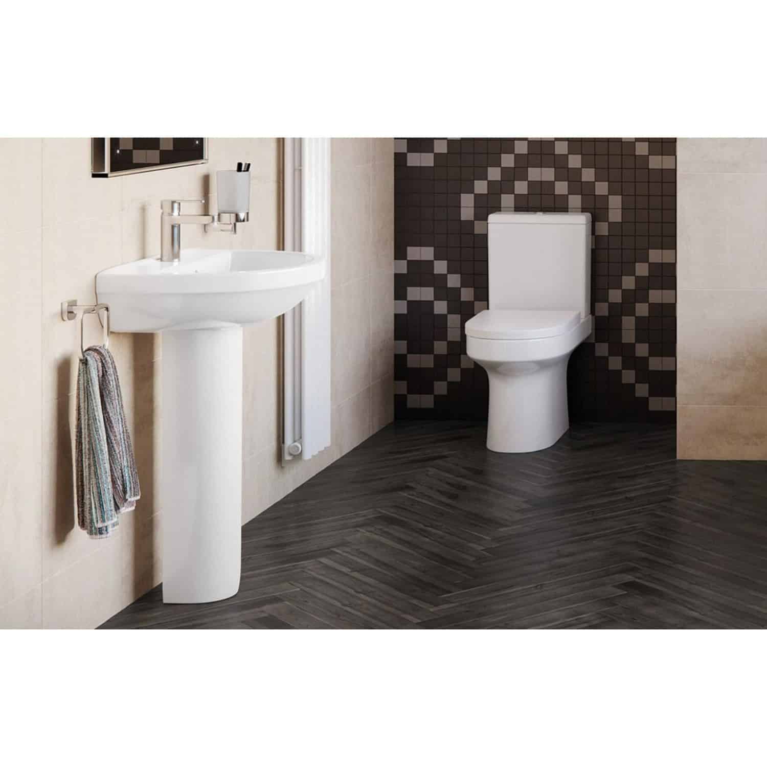 Sleek white bathroom sink with chrome faucet and towel hook, modern design with beige tiled walls, contrasted by dark herringbone wood-effect flooring, clean and contemporary bathroom setup.