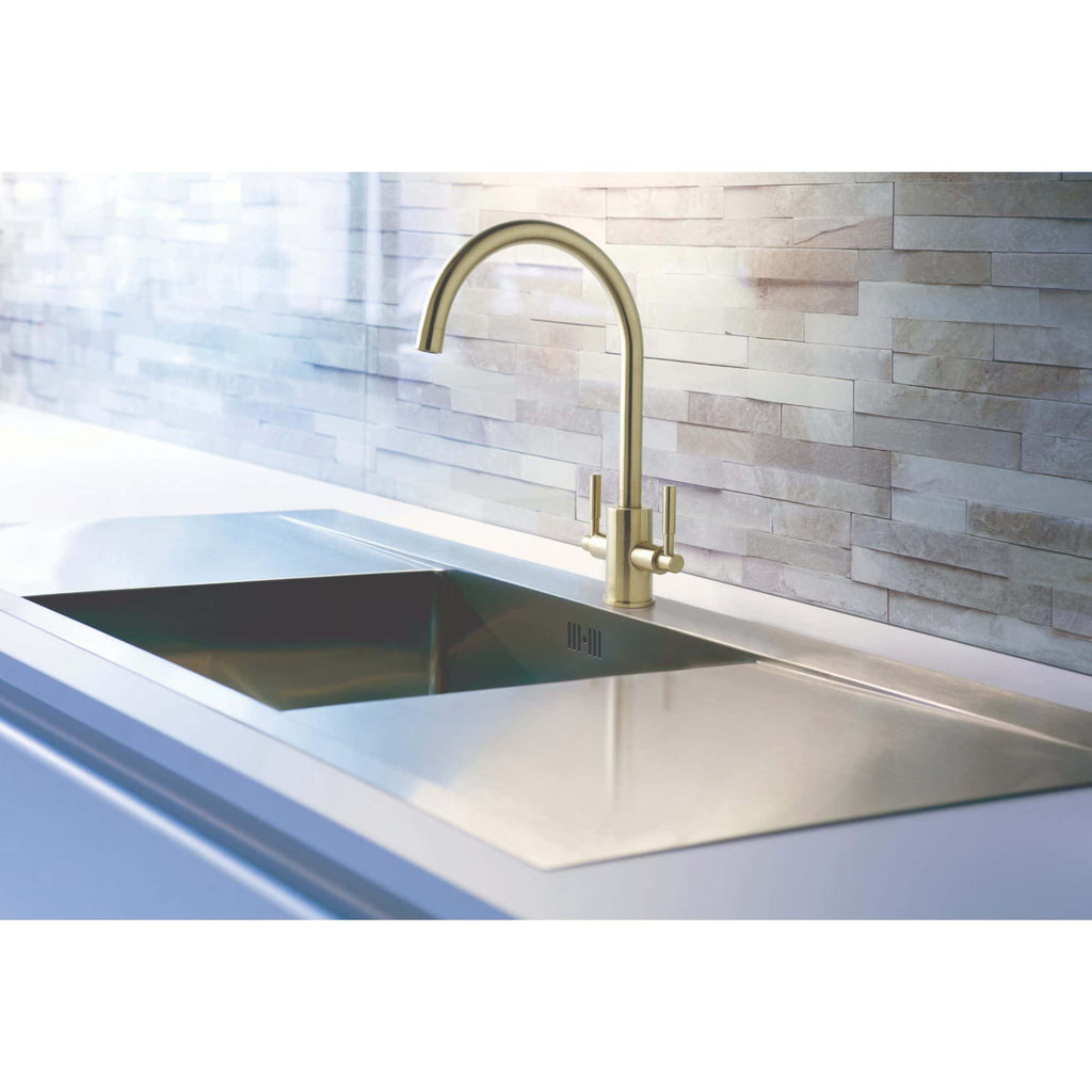Sleek stainless steel kitchen sink with modern gold-finish faucet against a stylish stone tiled backsplash, perfect for contemporary bathroom or kitchen design.