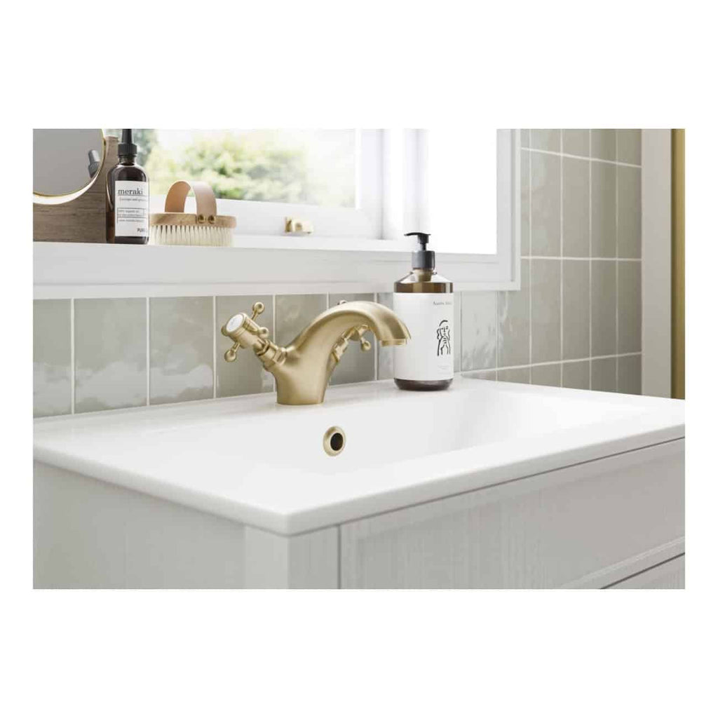Vintage gold bathroom sink and tap with skincare products in a modern bathroom setting.