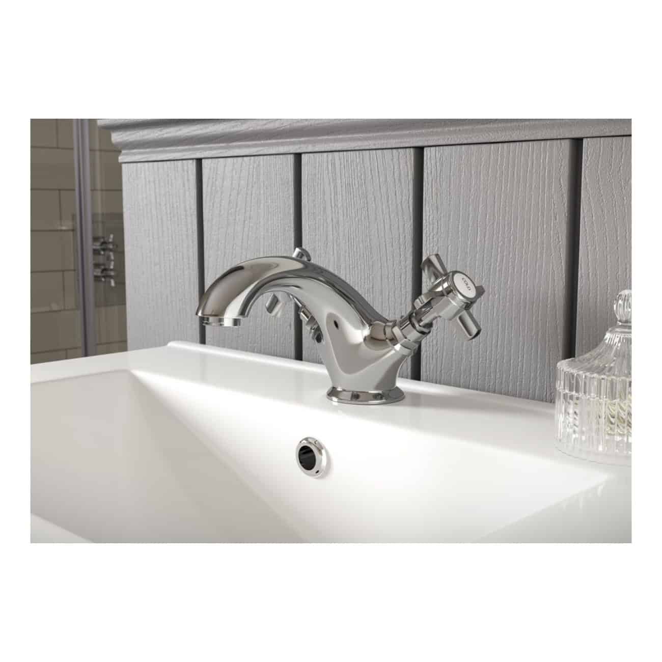 Shiny chrome bathroom sink mixer tap installed on a white ceramic basin in a modern bathroom setting.