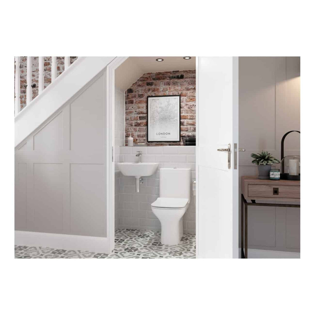 Modern small bathroom with white fixtures, exposed brick wall, and patterned floor tiles, featuring a toilet, sink, and stylish decor, ideal for contemporary bathroom design.
