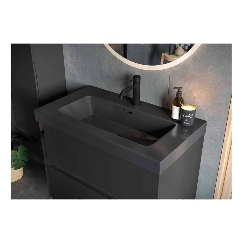 Black modern bathroom vanity with integrated rectangular sink and matte black faucet, mounted on a grey tiled wall, accessorised with soap dispenser and candle, reflecting contemporary bathroom style in a sleek design.