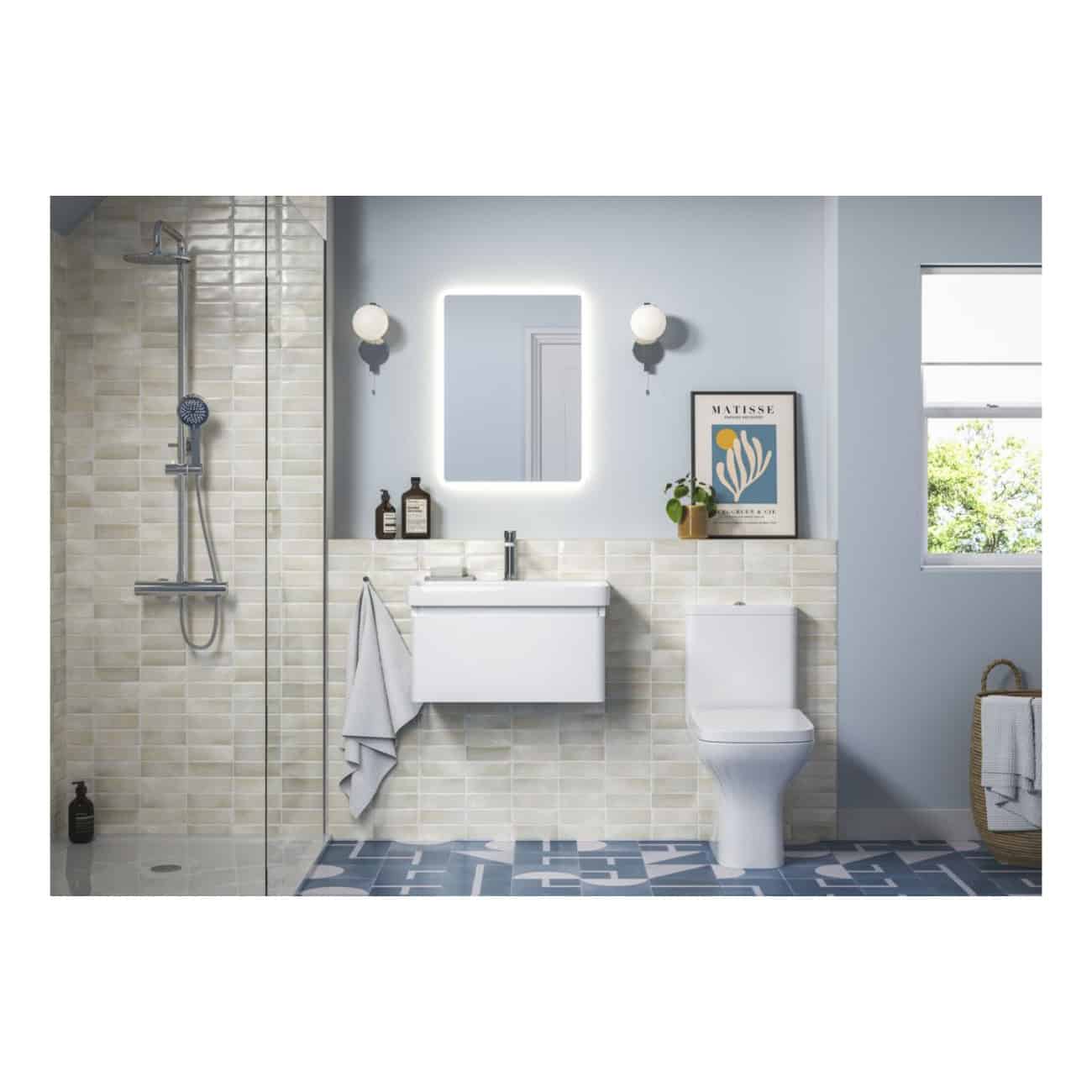 Bright modern bathroom with walk-in shower, white vanity, toilet, decorative mirror with LED lighting, stylish wall-mounted light fixtures, framed artwork, and natural light from a window.