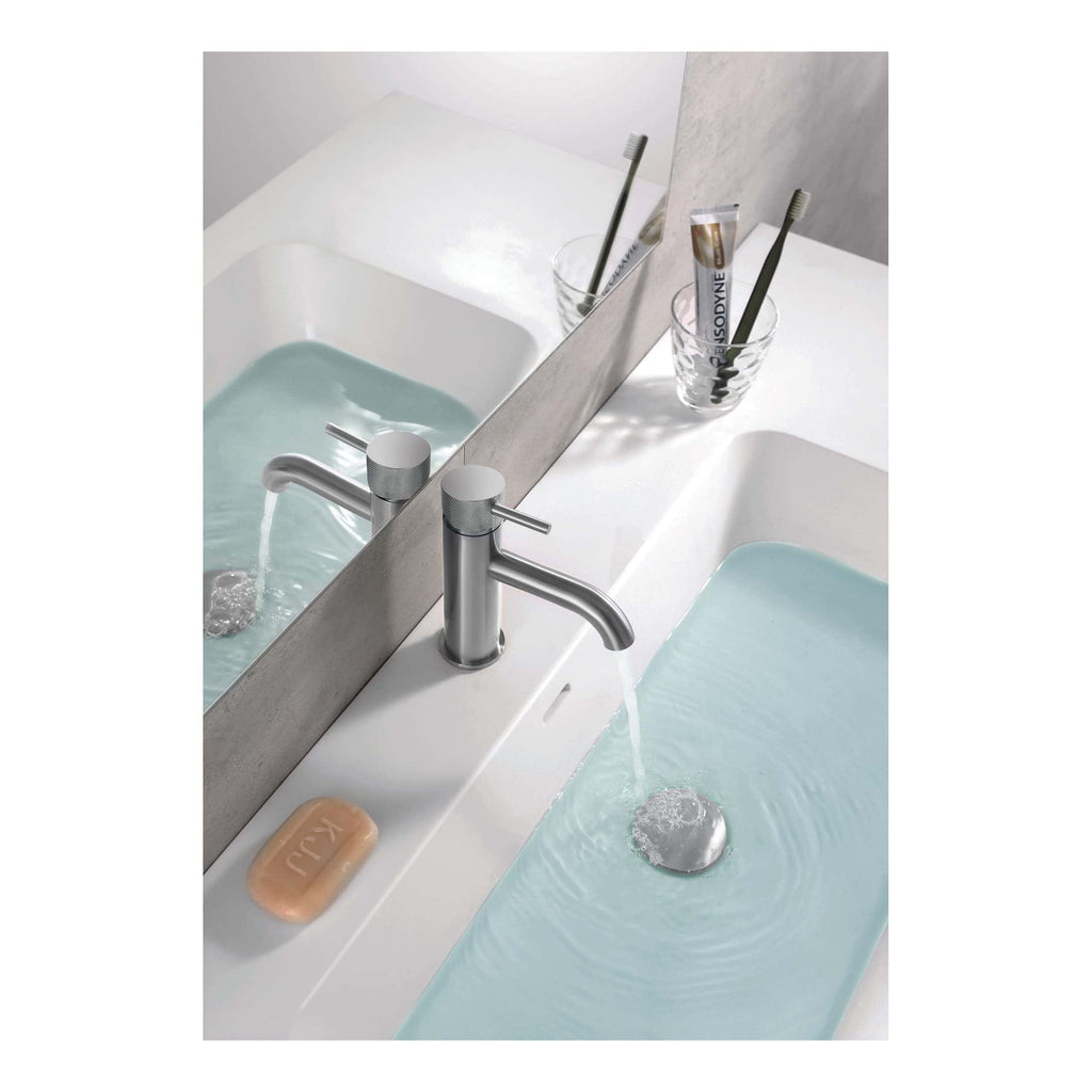 Deep bathroom sink with modern silver faucet and light blue water, clean white countertop with soap bar and toothbrush holder, large mirror reflecting the sink area, minimalist bathroom design with functional fixtures and subtle decor for hygiene and style.