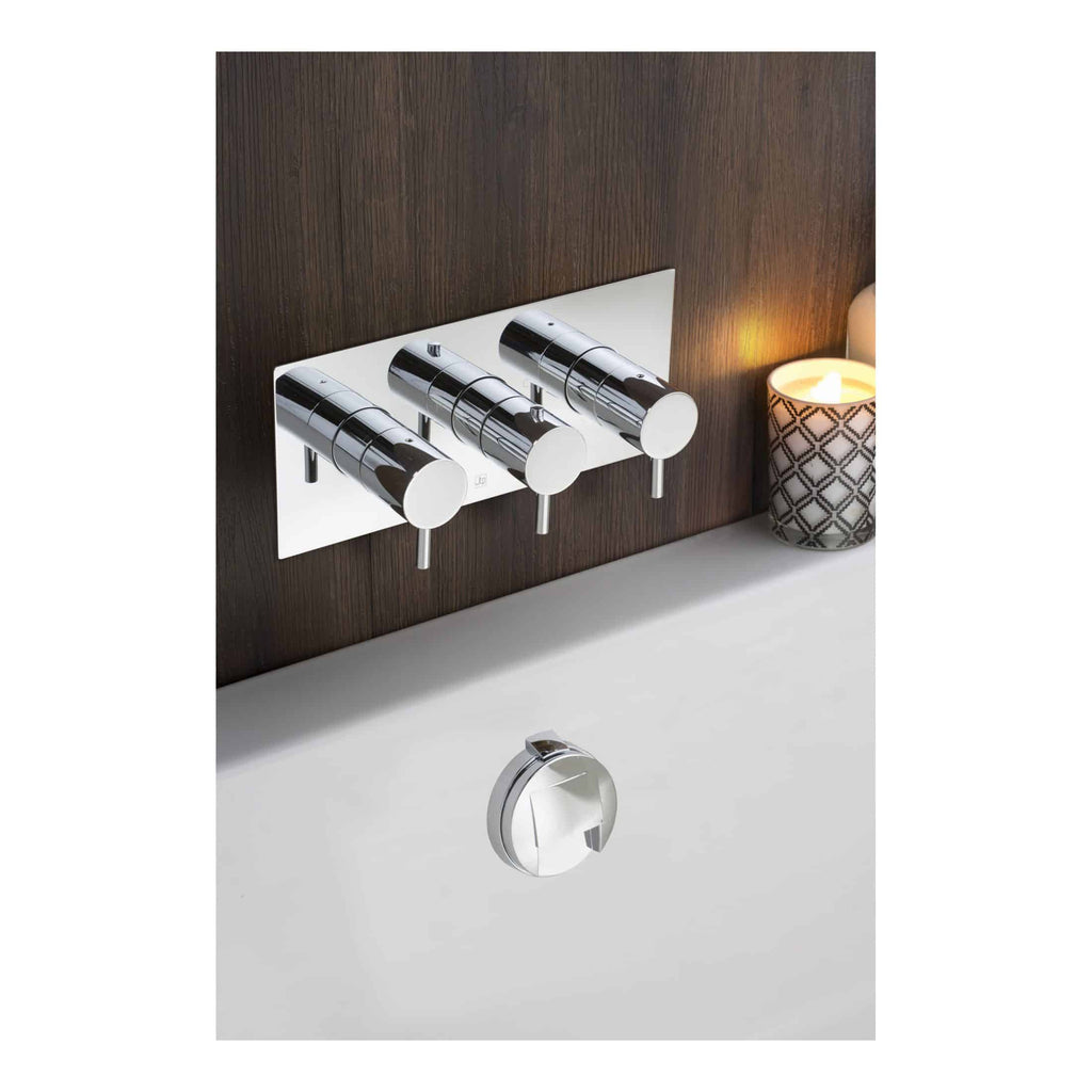 Sleek modern chrome bathroom tap with three control handles, mounted on a white and dark wood wall, ideal for contemporary bathroom designs.