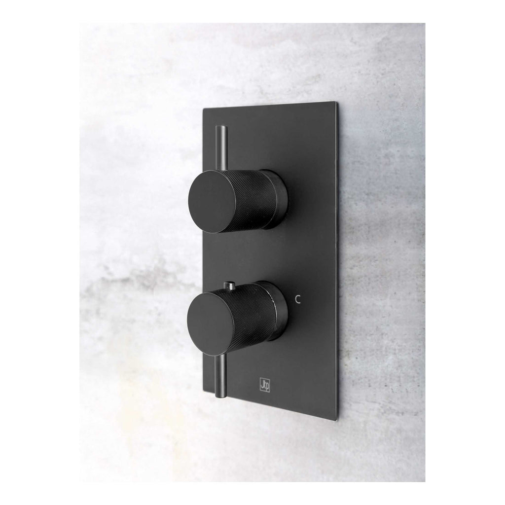 Sleek black thermostatic shower control panel with dual knobs for precise temperature and flow adjustment, mounted on a light grey tiled wall. Perfect for modern bathroom renovations or upgrades.