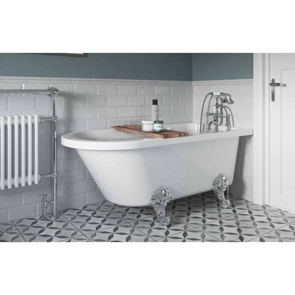 Luxurious vintage-style bathtub with ornate clawfoot design in a modern bathroom with geometric black and white tiled floor and white brick wall. Features chrome fixtures and a wooden tray.