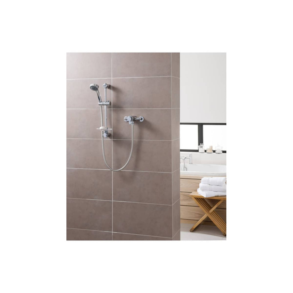 Chrome bathroom shower rail and handheld shower head in a modern, tiled wet room setting with beige wall tiles.