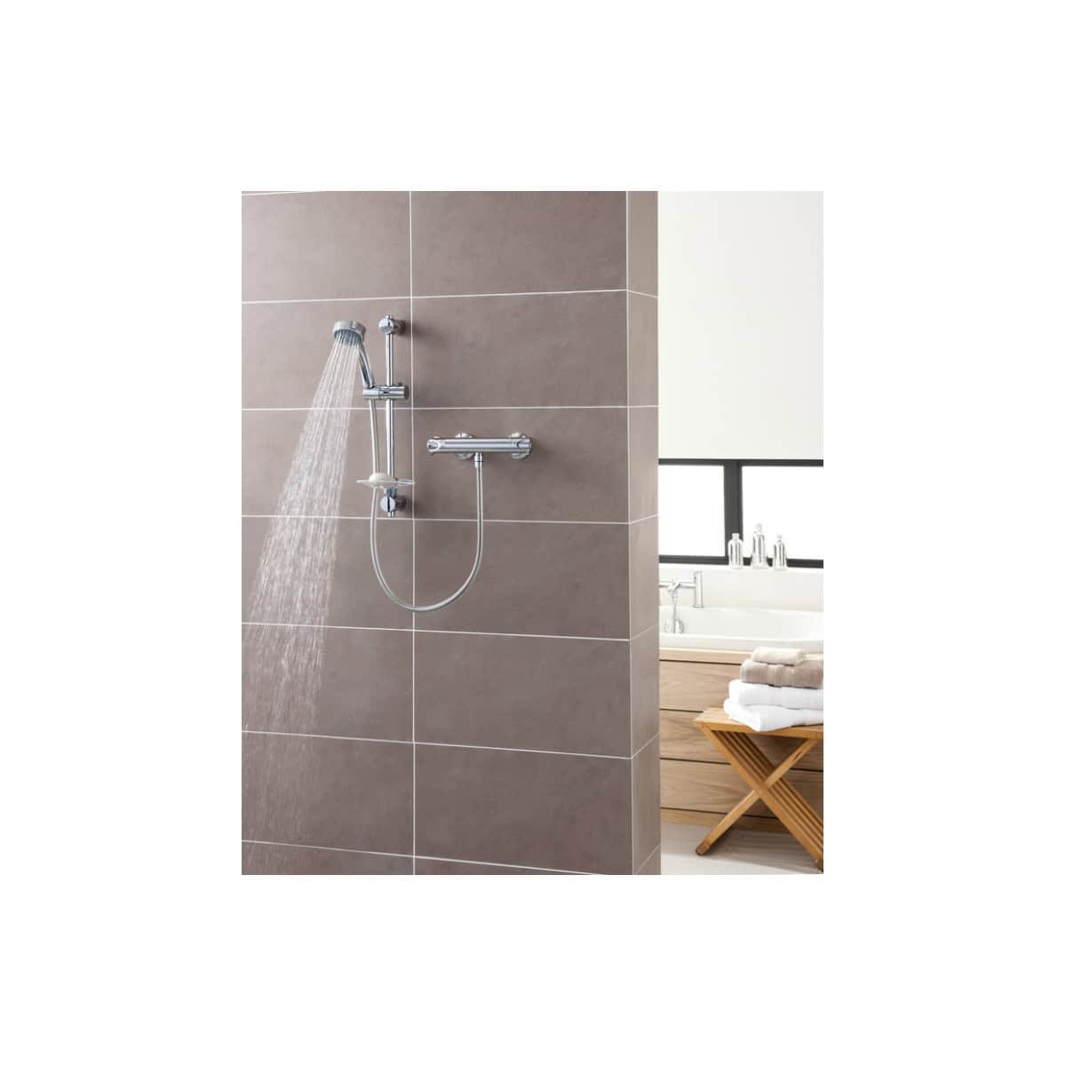 Modern chrome shower head and handheld shower system in a contemporary bathroom setting with beige tiles.