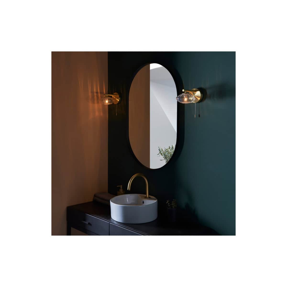 Modern bathroom vanity with sleek black cabinetry, a stylish oval mirror, and contemporary gold wall sconces for a luxurious bathroom design. Perfect for elegant bathroom renovations.