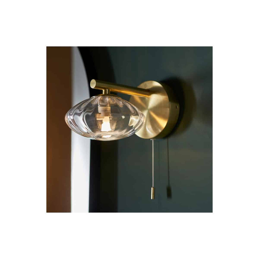 Elegant modern bathroom wall light with a clear glass shade and brass finish, ideal for bathroom lighting, adding sophistication and ambient illumination to your bathroom space.