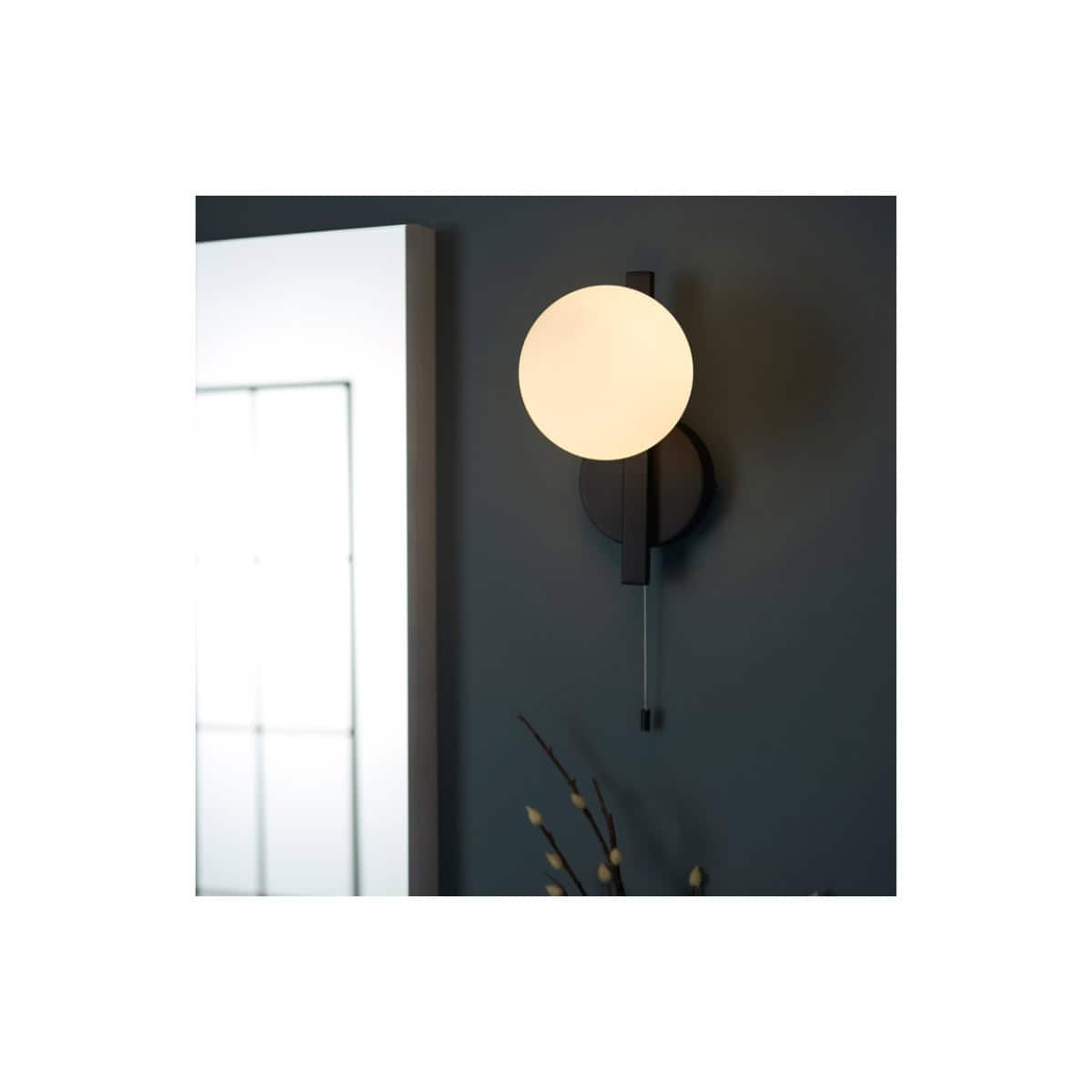 Modern wall-mounted bathroom sconce with round white globe light and black fixture, ideal for contemporary bathroom lighting.
