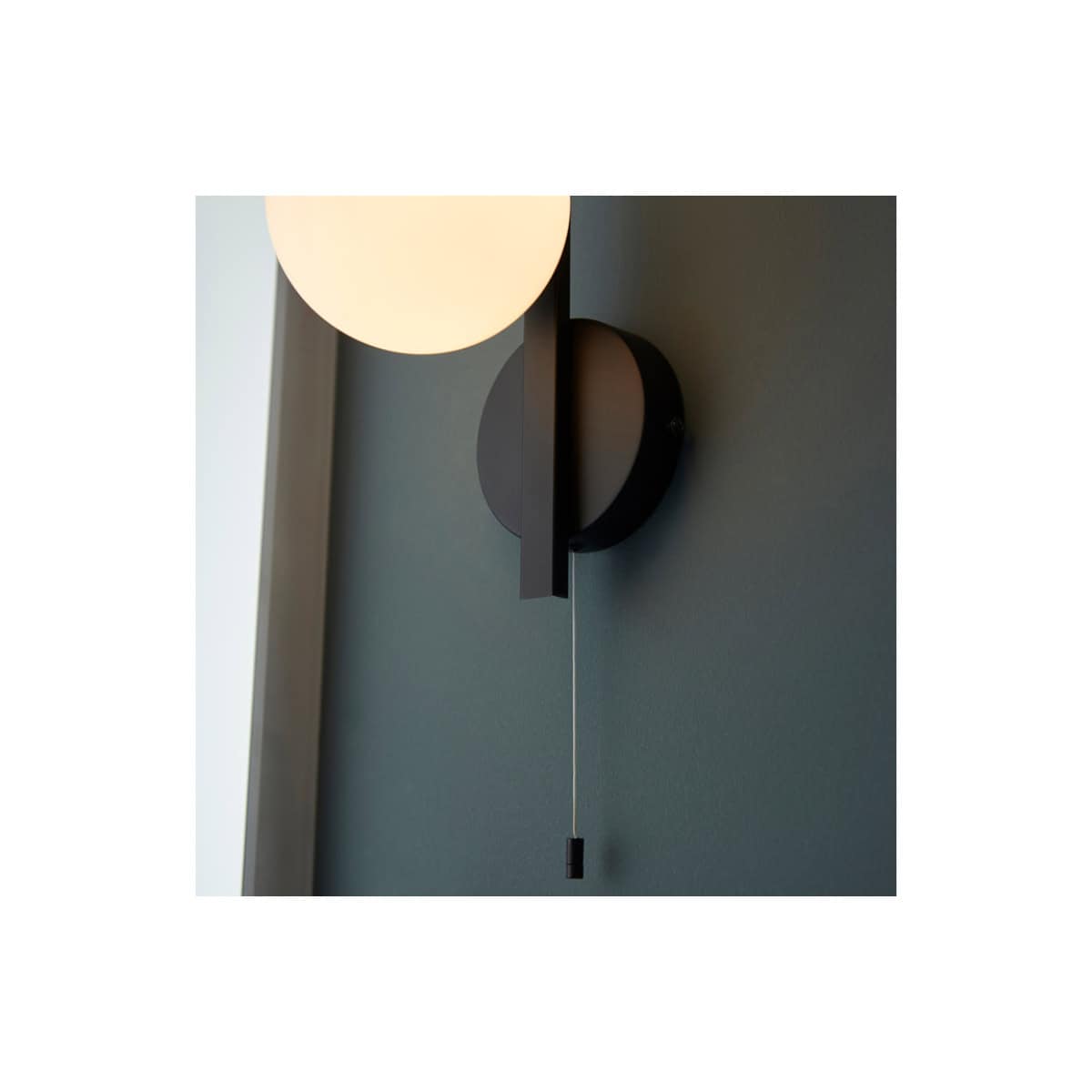 Sleek modern wall light fixture with a round frosted glass shade and black mounting wall, ideal for contemporary bathrooms and lighting design.