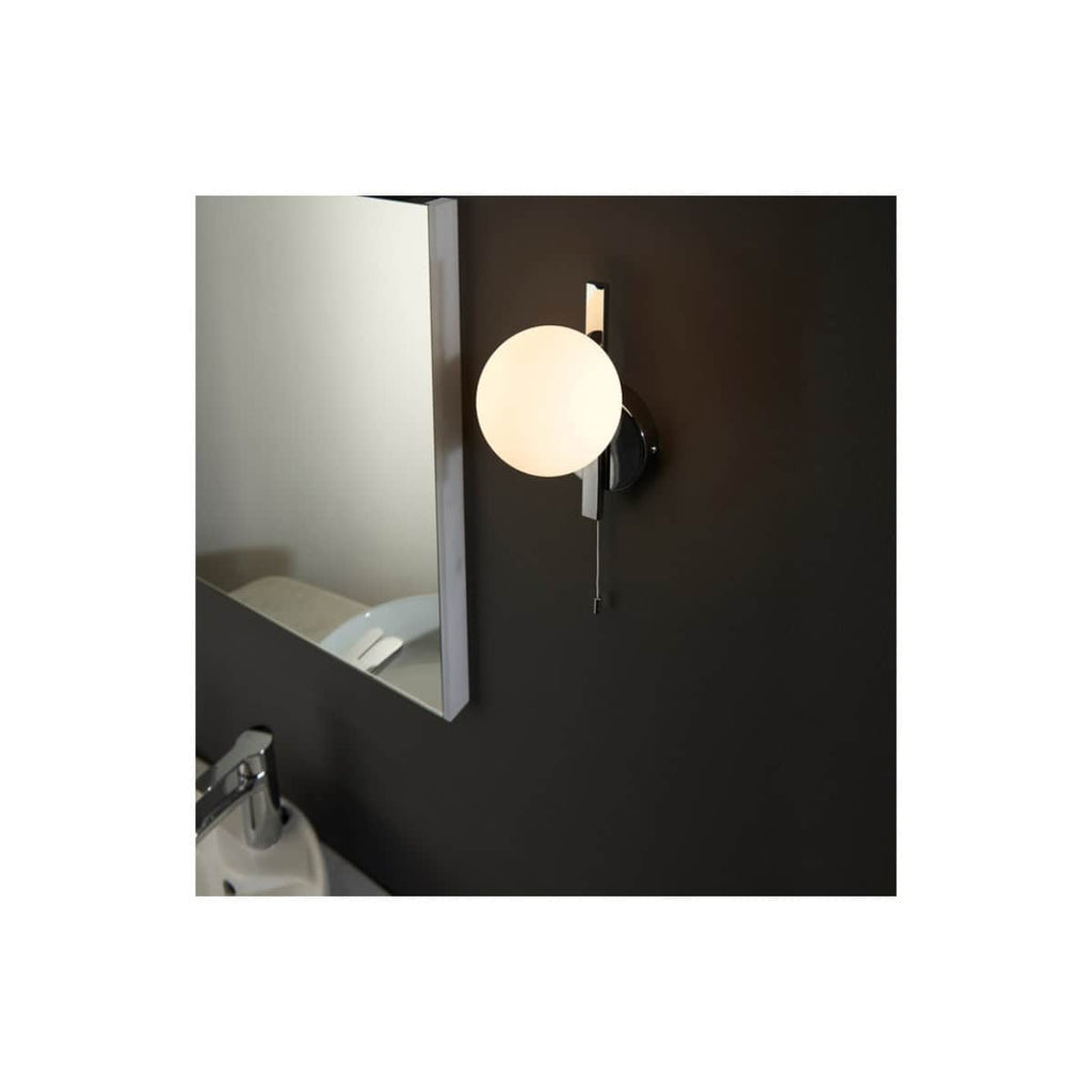 Modern black wall-mounted bathroom sconce with frosted globe light near bathroom mirror and sink, ideal for contemporary bathroom lighting decor.