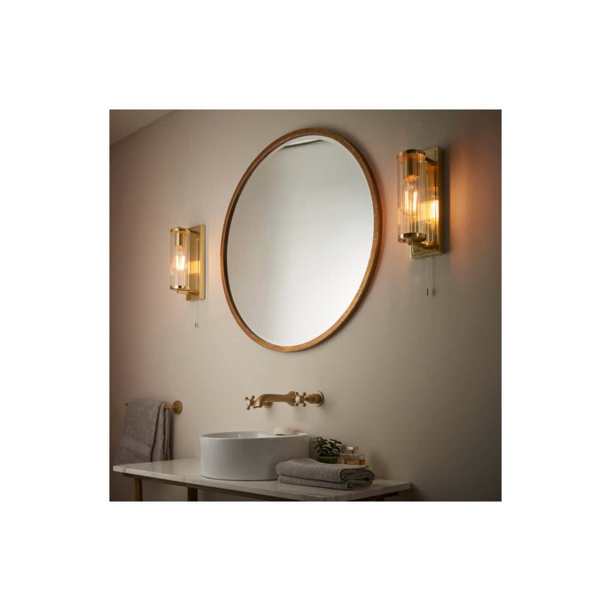 Modern bathroom with round mirror, gold wall sconces, and white vessel sink for stylish bathroom decor.