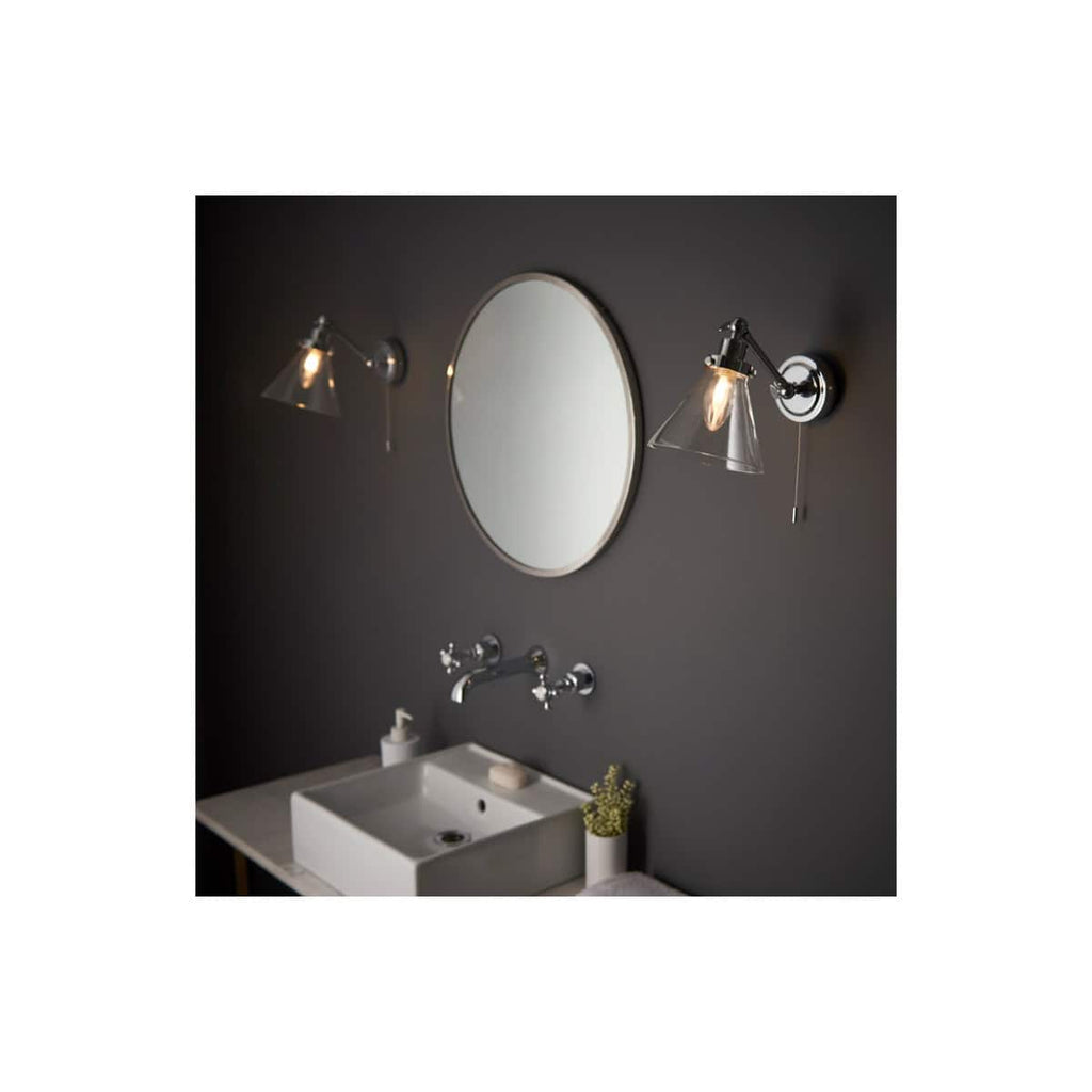 Modern bathroom lighting with stylish wall sconces and a sleek oval mirror. The setup enhances bathroom aesthetics and functionality, perfect for contemporary bathroom designs.