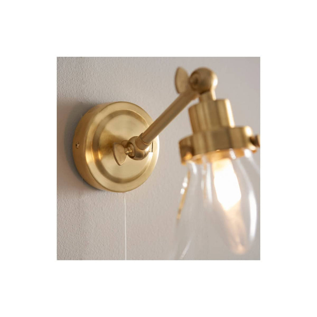 Polished brass wall-mounted bathroom light fixture with clear glass shade, perfect for elegant bathroom decor and lighting; designed by Bubly Bathrooms.