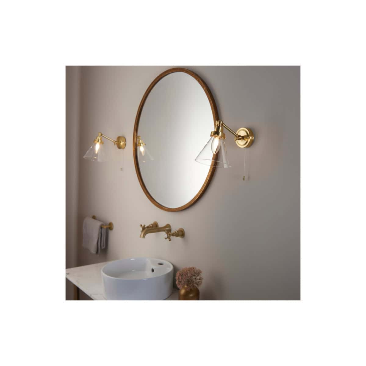 Polished gold wall sconces with glass shades illuminating a modern bathroom mirror above a white vessel sink. Elegant bathroom lighting and fixtures create a stylish, functional space.
