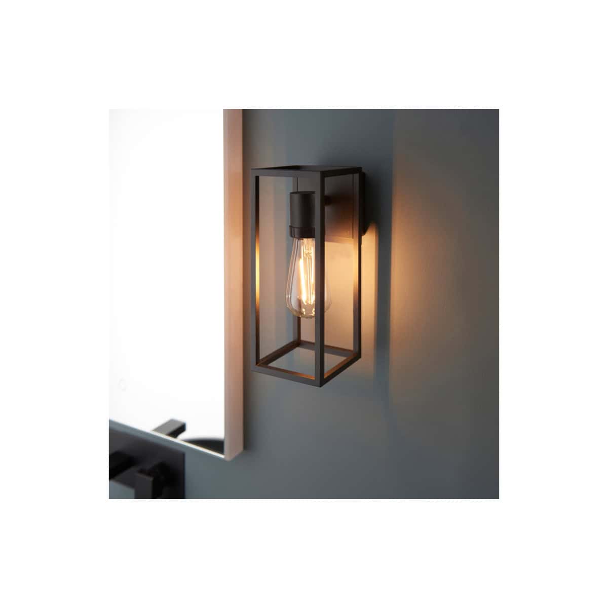 Modern industrial wall sconce with exposed filament bulb, black metal frame, ideal for contemporary bathroom lighting and decor, energy-efficient LED compatible, enhances bathroom ambiance.