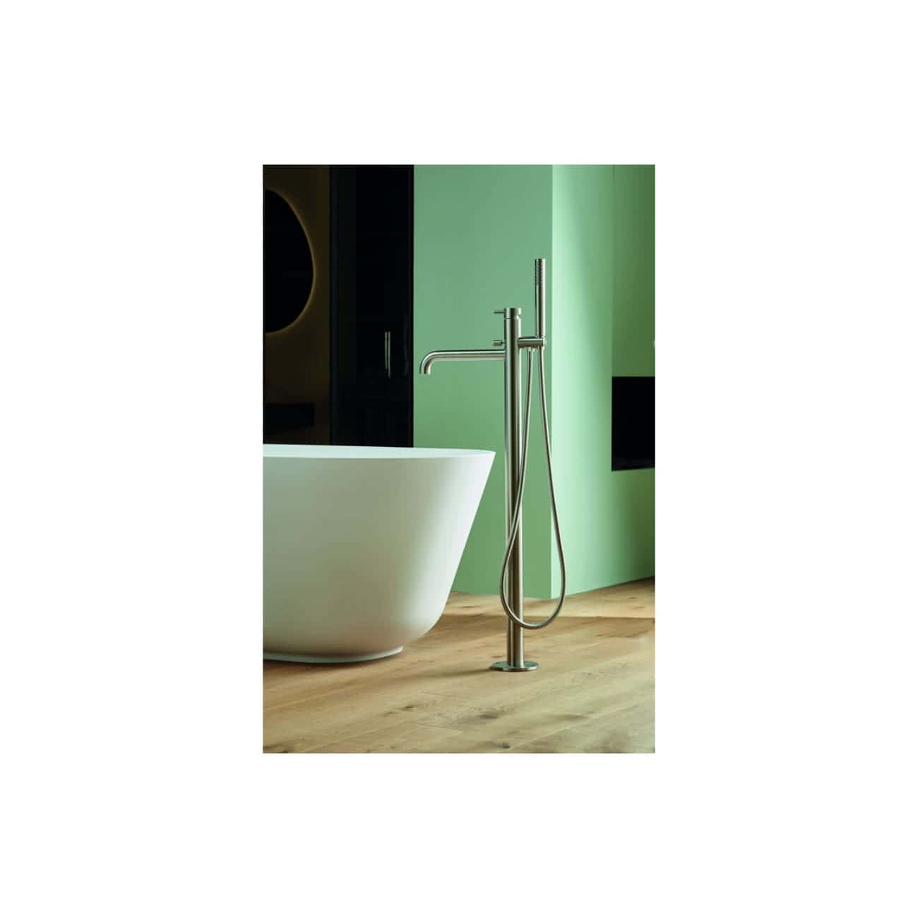 Polished modern freestanding bathtub with sleek chrome bathroom tap and handheld shower, set against vibrant green walls and wooden flooring, showcasing luxury bathroom design and fixtures.