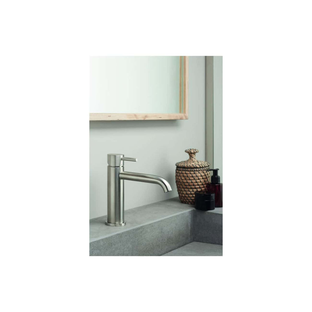 Sleek stainless steel bathroom sink tap on a minimalist grey stone counter with decorative wicker jar and black soap dispenser, perfect for modern Bubly bathrooms in the UK.