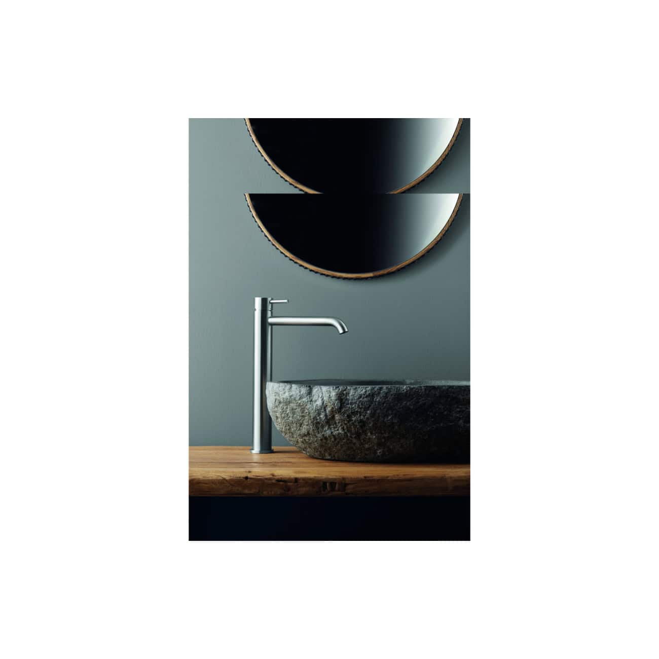 Sleek modern bathroom sink with a stone vessel basin and minimalist chrome tap, surrounded by contemporary wall mirrors and stylish wooden countertop for a luxurious bathroom design.