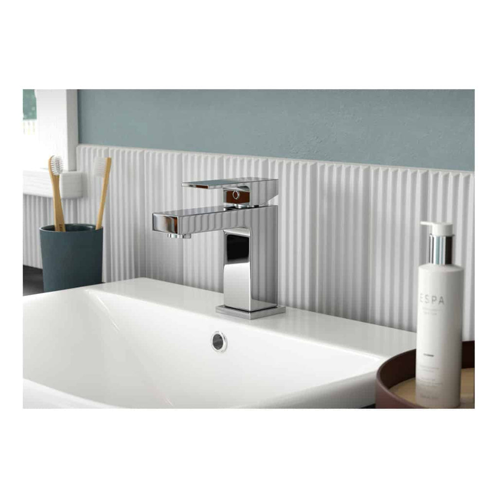 Sleek modern bathroom sink with chrome faucet, set against a textured white tile wall, complemented by bathroom accessories and personal care products for a contemporary bathroom look.