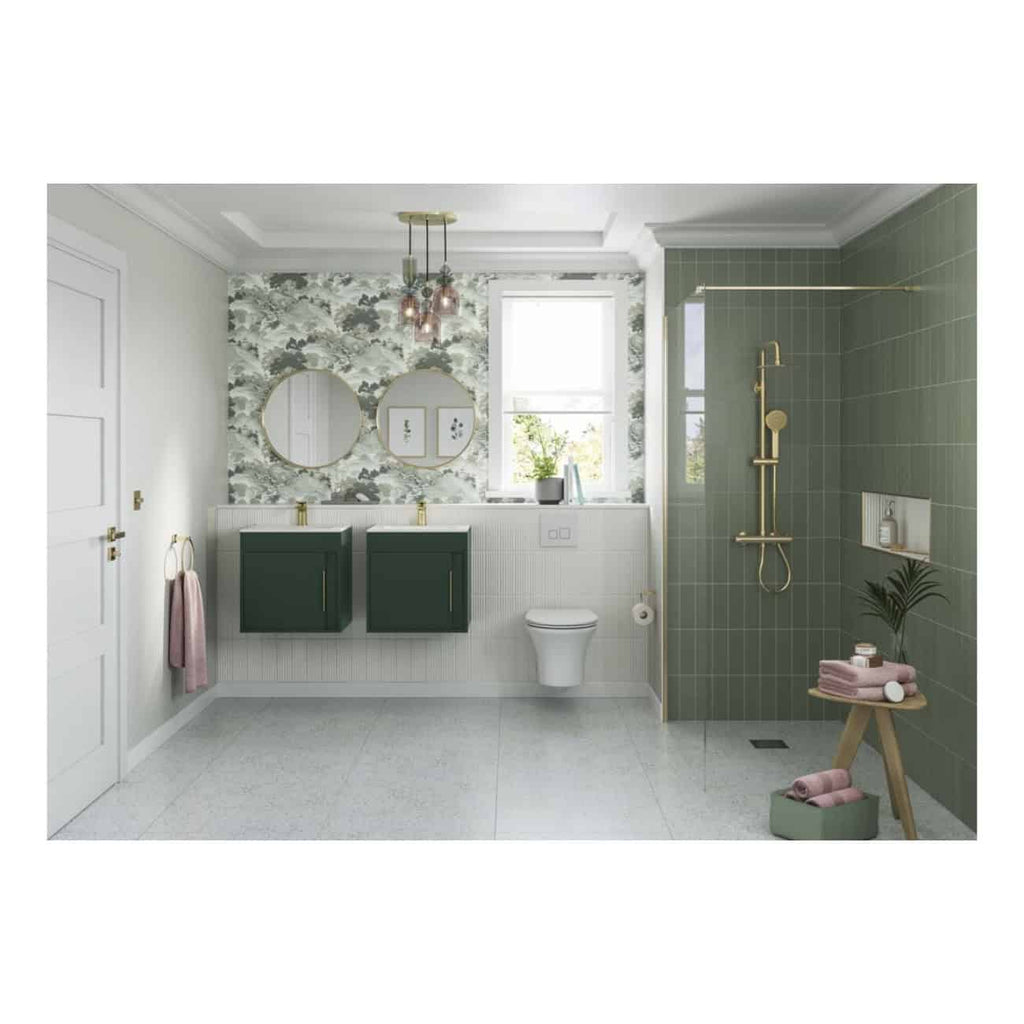 Bright modern bathroom with green vanity units, patterned wallpaper, and sleek fixtures including a wall-mounted toilet and walk-in shower with gold accents, natural light from a large window, and stylish decor.