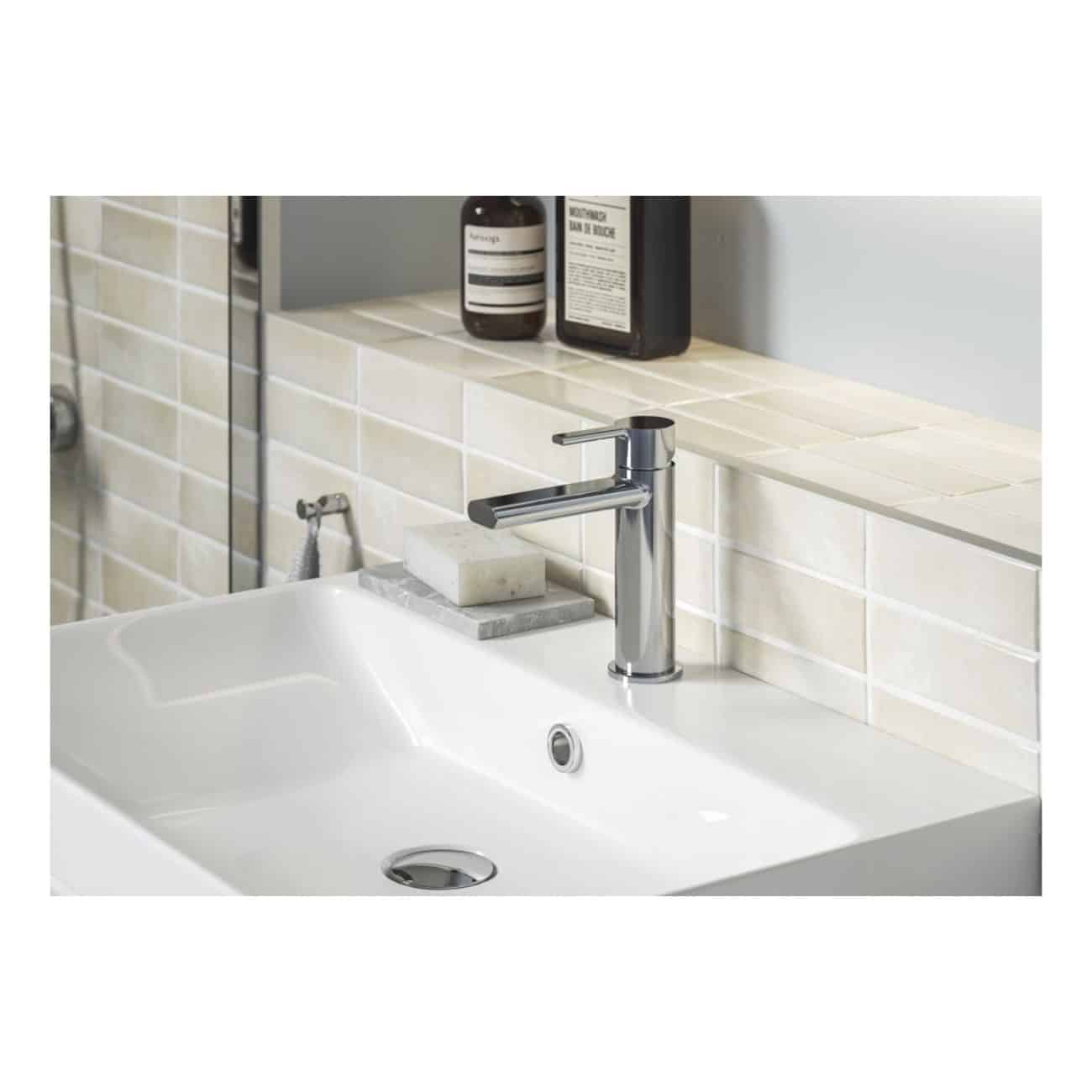 Shiny chrome bathroom sink tap with beige tiled backsplash and soap on a marble tray, modern clean design, ideal for contemporary bathroom renovation or renovation projects.