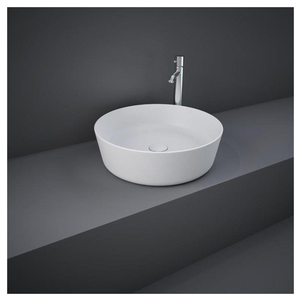 Sleek white vessel bathroom sink with chrome faucet on grey countertop and dark wall background, modern bathroom basin design.
