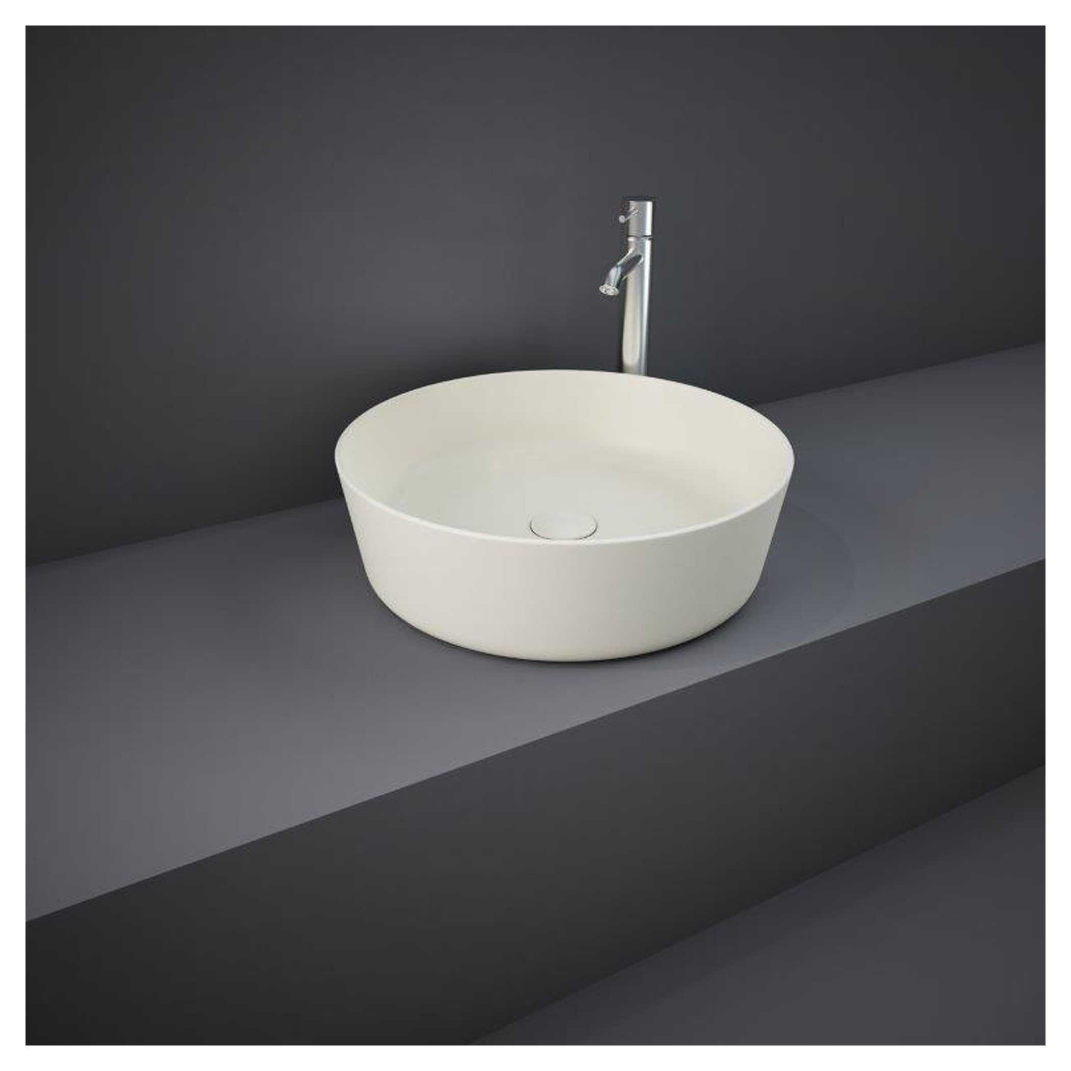 Sleek white vessel bathroom sink with modern chrome tap on grey countertop against dark wall.